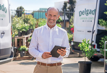 man holding a tablet and standing outside at a landscaping center