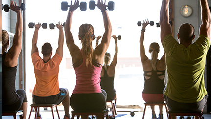 Men and women doing shoulder presses with dumbbells