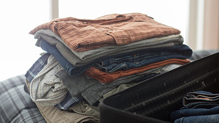 folded clothes sitting next to a suitcase