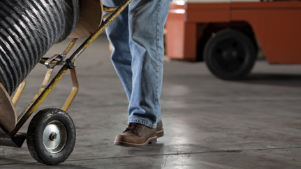 worker pushing a spool of cable on a dolly