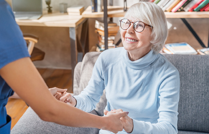 A retired woman smiles and holds hands with her daughter.