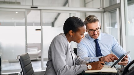 Man and woman reading tablet at desk