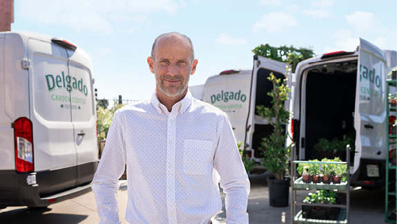 Smiling man standing in front of 2 commercial vans